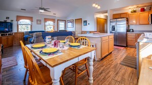 A modern kitchen with wooden cabinets, a central island, and a dining area with a wooden table and chairs. - Waterfront, Dog friendly, & private boat ramp (Frisco)