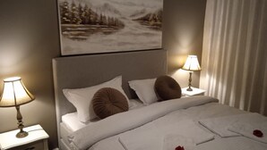 Habitació d'hotel amb un llit, dues làmpades de nit, un quadre sobre el llit i una finestra amb cortines.