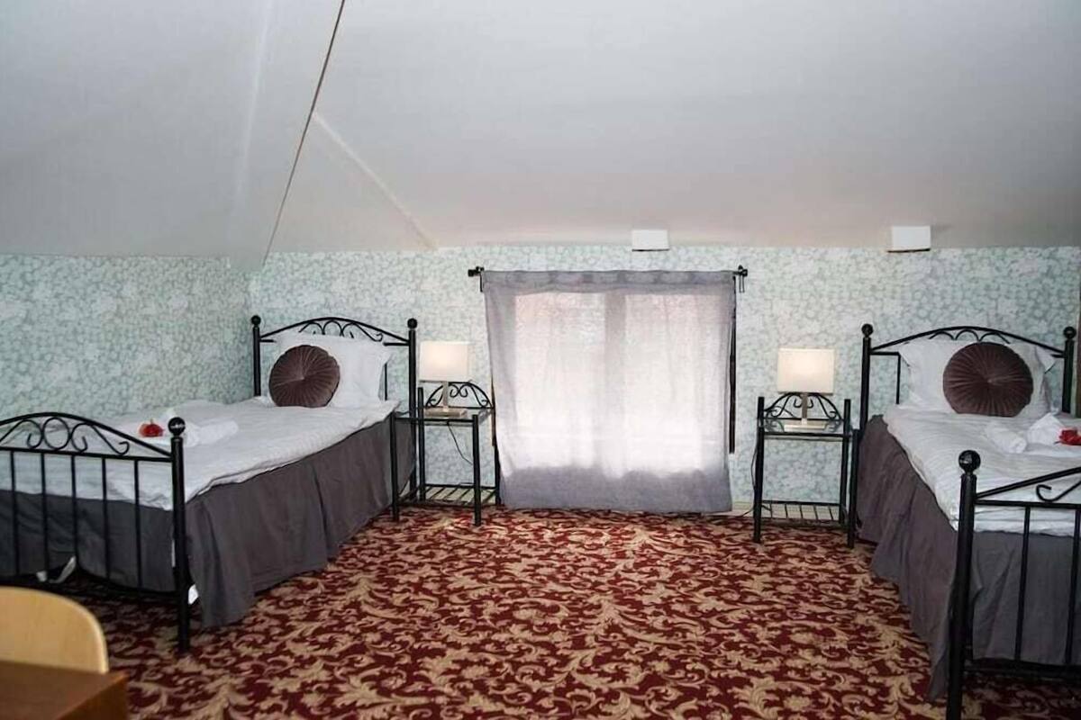 A room with two beds, a small table, and a chair.