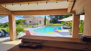 A wooden deck with a pool, lounge chairs, and a pink flamingo float. - Provençal Villa in the Heart of Sainte-Victoire (Saint-Antonin-sur-Bayon)