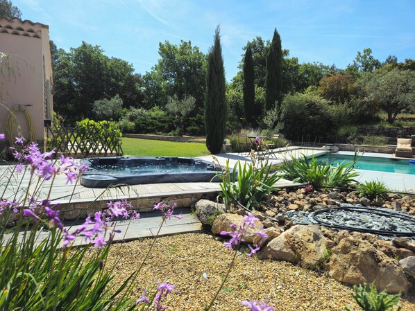 Un patio trasero con un jacuzzi, una piscina y una terraza de madera.