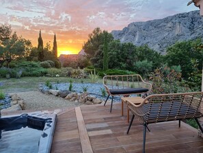 Una terraza de madera con dos sillas de mimbre y un jacuzzi.