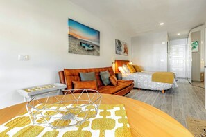 Ein modernes Wohnzimmer mit einer Couch, einem Bett und einem Esstisch mit geometrischer Dekoration.