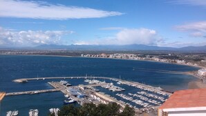 A marina with boats docked, surrounded by a coastal town with buildings and mountains in the background. - APT 3 BEDROOMS TERRACE SEA VIEW BEACH ROSAS - NEW AIR CONDITIONING- PRIVATE PARKING (Roses ( petites Canyelles ))