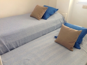 A twin bed with a herringbone-patterned blue and white bedding, two brown pillows, and a white headboard. - APT 3 BEDROOMS TERRACE SEA VIEW BEACH ROSAS - NEW AIR CONDITIONING- PRIVATE PARKING (Roses ( petites Canyelles ))