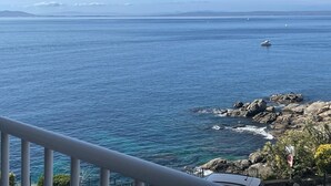 A coastal view with a rocky shoreline, a boat in the distance, and a clear sky. - APT 3 BEDROOMS TERRACE SEA VIEW BEACH ROSAS - NEW AIR CONDITIONING- PRIVATE PARKING (Roses ( petites Canyelles ))