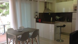 A modern kitchen with white cabinets, a stainless steel range hood, and a bar stool. - APT 3 BEDROOMS TERRACE SEA VIEW BEACH ROSAS - NEW AIR CONDITIONING- PRIVATE PARKING (Roses ( petites Canyelles ))