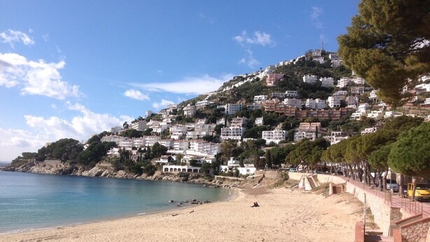 A beach with a staircase leading to a building with multiple floors, surrounded by trees and overlooking the sea. - APT 3 BEDROOMS TERRACE SEA VIEW BEACH ROSAS - NEW AIR CONDITIONING- PRIVATE PARKING (Roses ( petites Canyelles ))