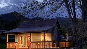 A log cabin with a welcoming front porch, a visible number '212', and a fenced yard.