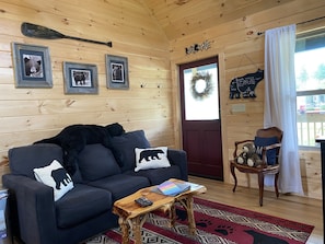 A cozy cabin interior with a dark blue sofa, a wooden coffee table, and a rug.