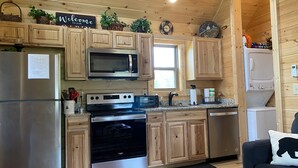 A modern kitchen with wooden cabinets, stainless steel appliances, and a welcome sign.
