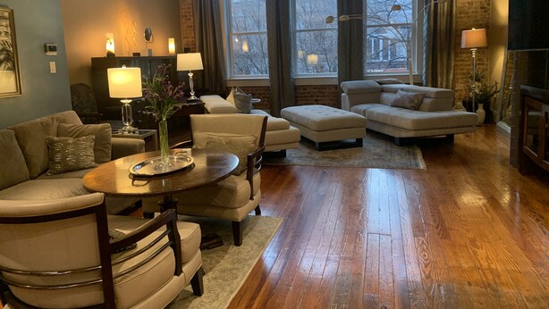 A spacious living room with a wooden floor, a large window, and a fireplace. - Historic Loft Main st. in the Heart of Downtown Greenville (Greenville)