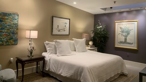 A bedroom with a bed, bedside tables, a lamp, and artwork on the walls. - Historic Loft Main st. in the Heart of Downtown Greenville (Greenville)