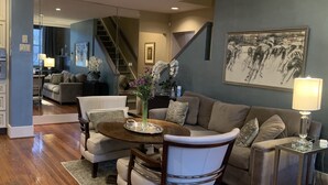 A modern living room with a dining area, featuring a sofa, chairs, a coffee table, and a painting on the wall. - Historic Loft Main st. in the Heart of Downtown Greenville (Greenville)