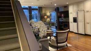 A modern kitchen with white cabinets, a dining area with a chair and table, and a staircase. - Historic Loft Main st. in the Heart of Downtown Greenville (Greenville)