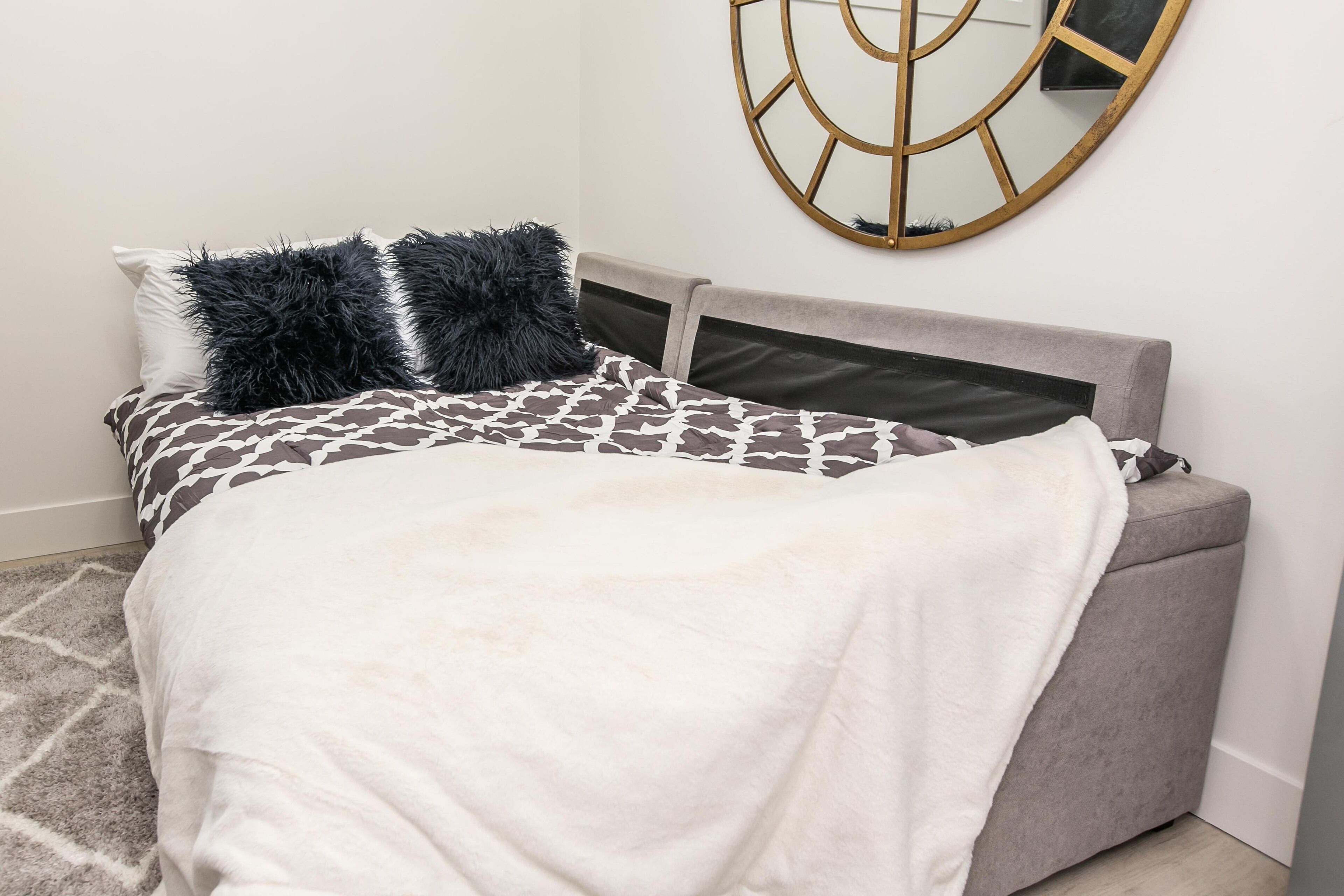 A neatly made bed with patterned bedding and a white throw blanket.