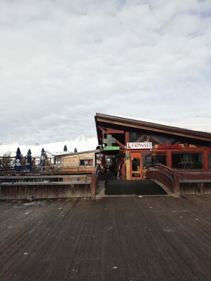 A wooden deck leading to a building with a sign reading 'L'ETRANGER Lounge Bar'. - Les Arcs 1800: Renovated 2-bedroom apartment in the Bellecote residence at the foot of the slopes (Bourg-Saint-Maurice)
