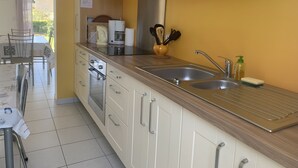 Een moderne keuken met roestvrijstalen apparatuur, een dubbele spoelbak en een houten aanrecht.