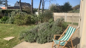 Een tuin met een houten stoel, een stenen bank en verschillende planten.