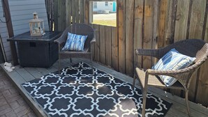 Un patio con dos sillas de mimbre, una mesita y un tapete estampado.