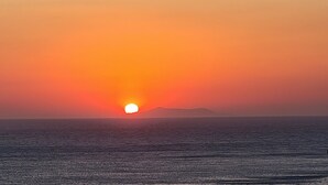 Un atardecer sobre el océano con un barco en primer plano.