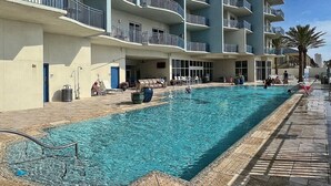 En swimmingpool som ligger intill en hög byggnad med flera våningar och balkonger.
