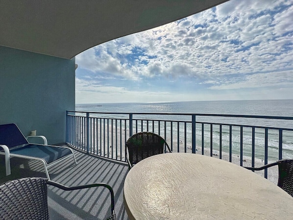 A balcony with a view of the ocean, featuring a table and chairs.