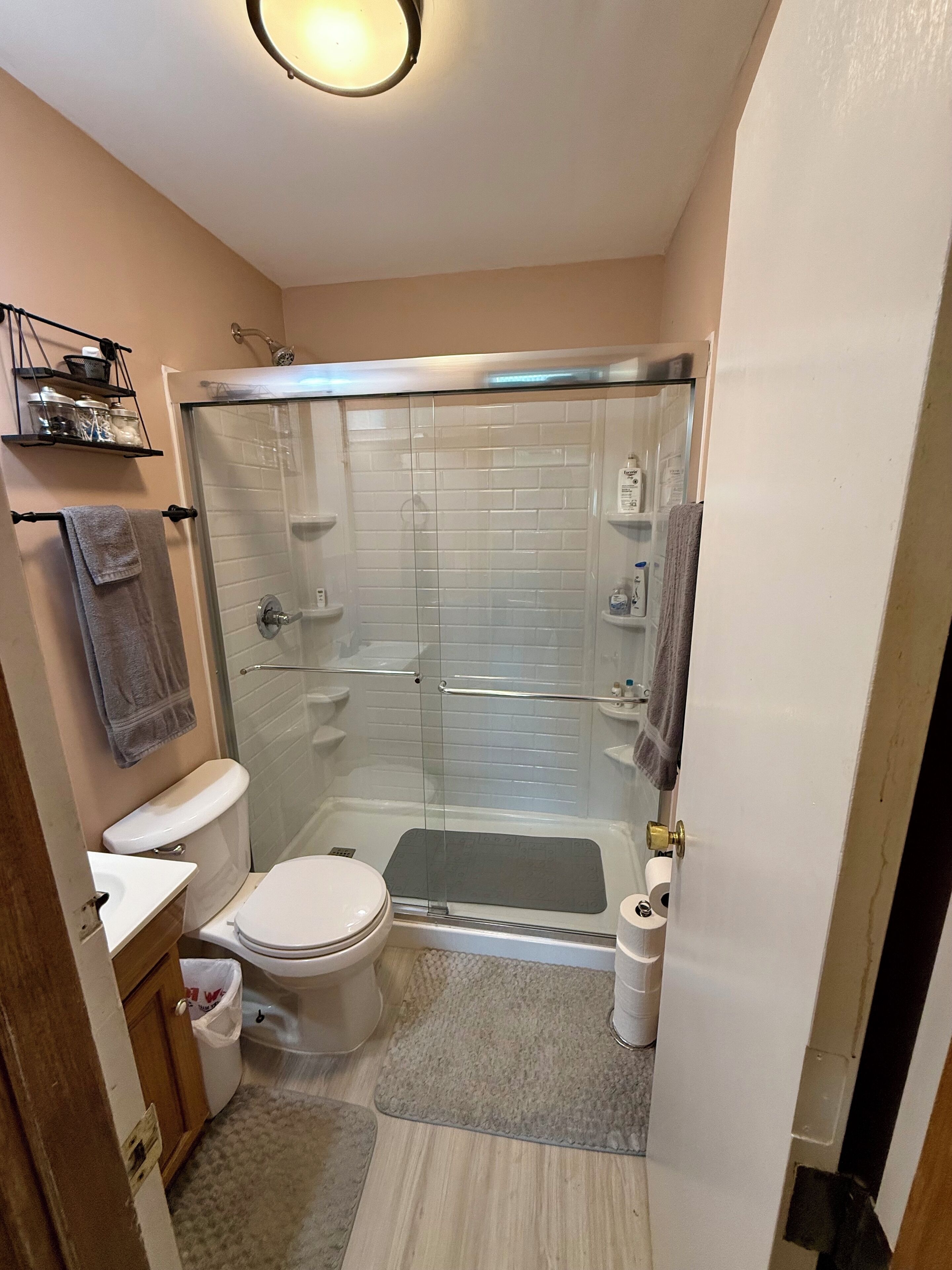 A compact bathroom with a glass-enclosed shower, a toilet, and a sink.