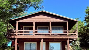 A two-story wooden house with a balcony, large windows, and a grassy front yard. - Relax and recharge at The Spot (Fall River)