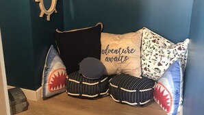 A cozy room with a dark blue wall, a skull and crossbones sign, a ship's wheel decoration, and a couch with nautical-themed pillows. - Sea Breezy Vacation House, Unit 2 - 5 min WALK to beach!! (Old Orchard Beach)