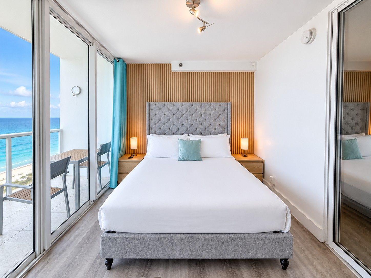 Habitació d'hotel amb un llit gran, vistes a la platja i un balcó amb taula i cadires.