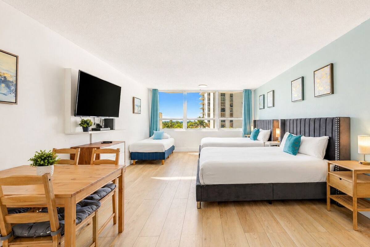 A hotel room with a bed, a desk, a TV, and a window with a view.
