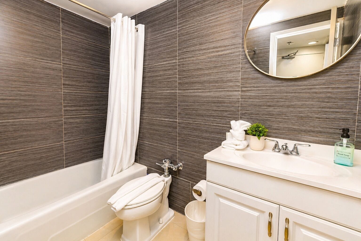 A bathroom with a bathtub, toilet, sink, and a mirror.