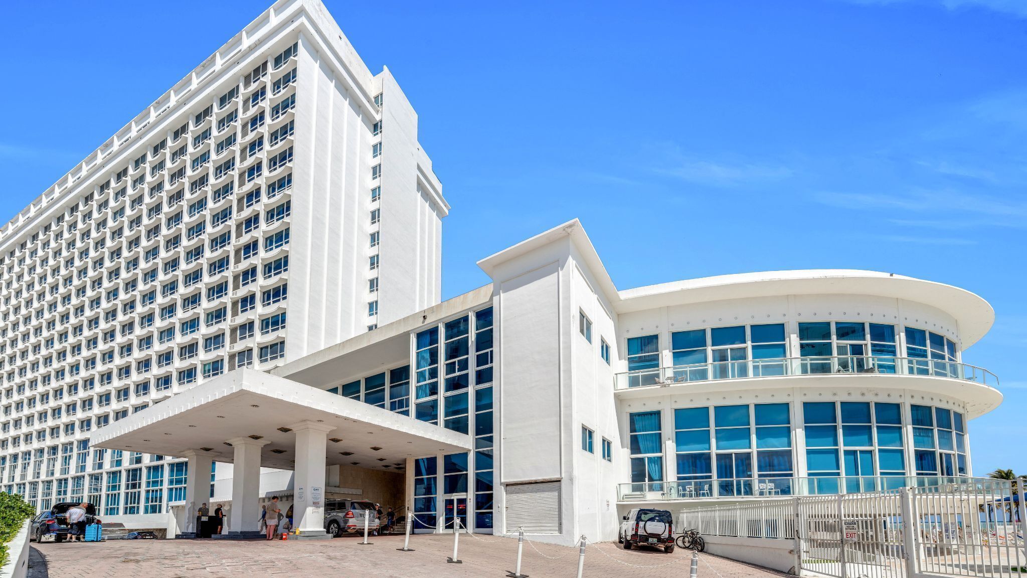 Un hotel con un edificio grande y blanco, y una estructura curva con ventanales amplios.
