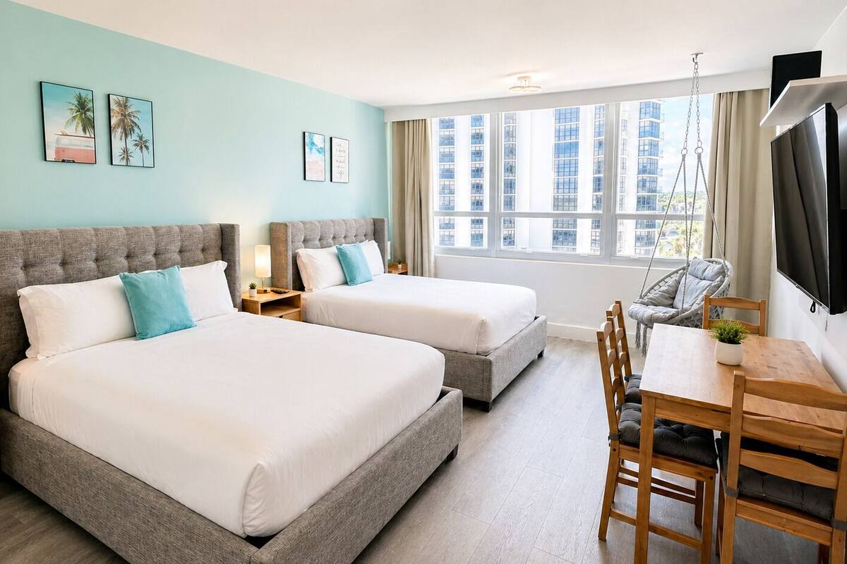 A hotel room with two beds, a desk, and a TV.