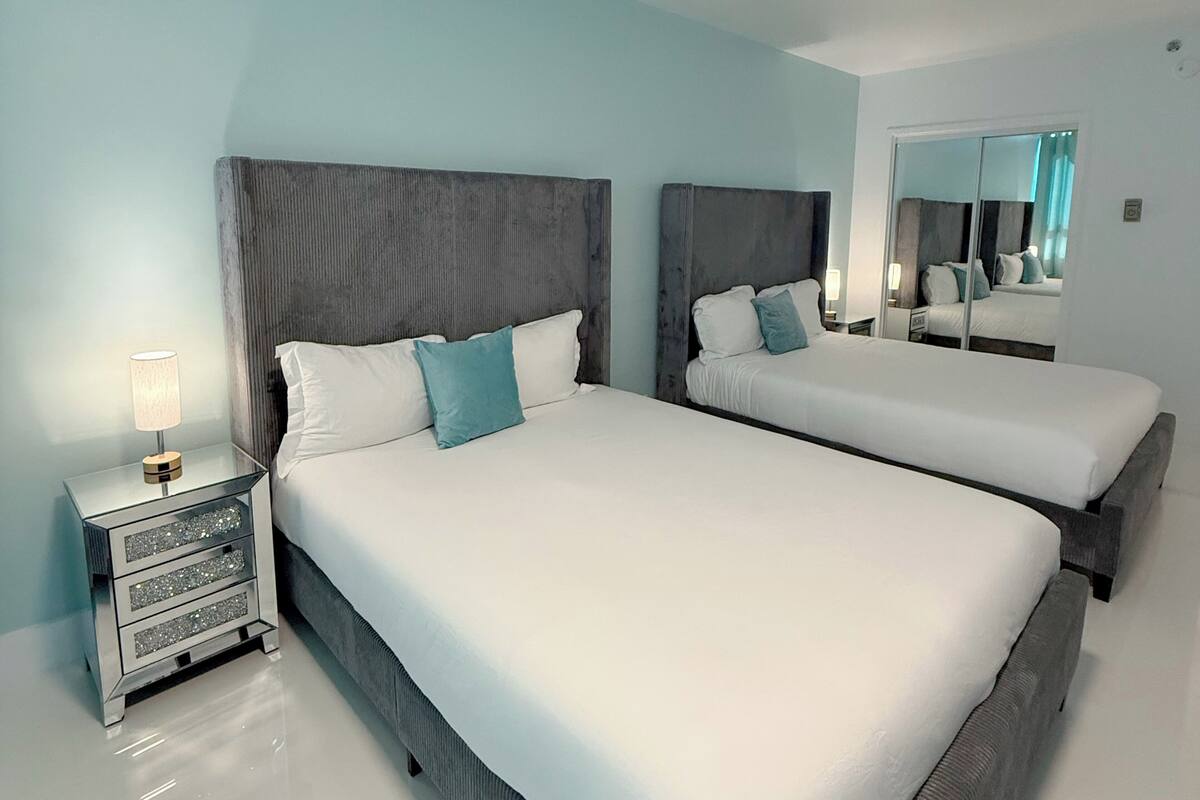 A hotel room with two beds, a nightstand, and a mirror.