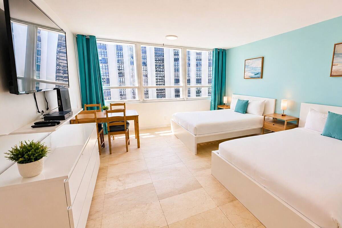 A hotel room with a bed, desk, chair, and a TV.