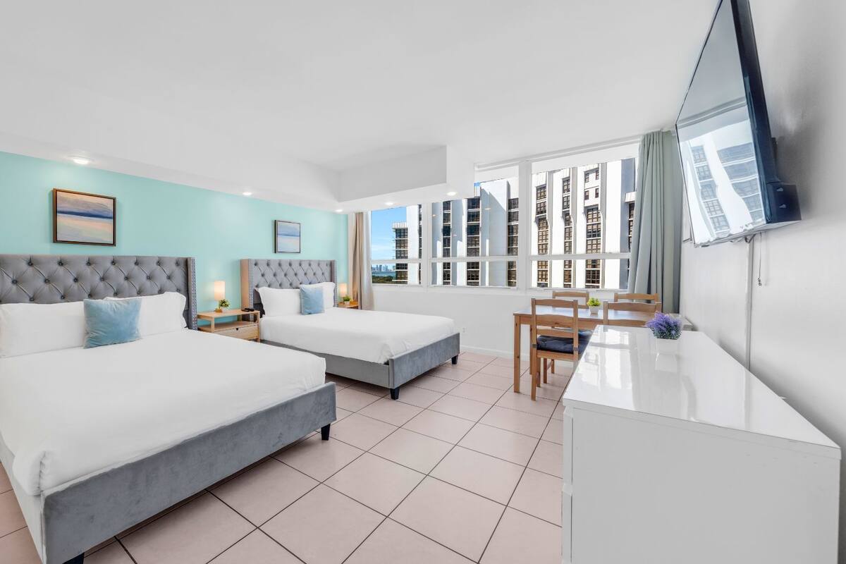 A hotel room with two beds, a desk, and a TV.