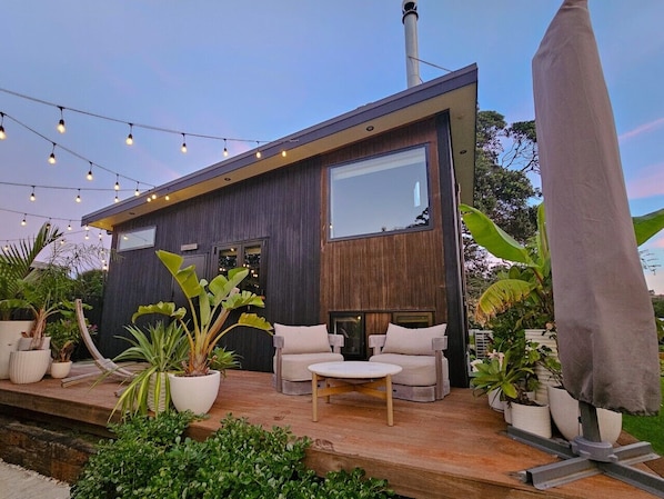 A modern building with a wooden deck, outdoor seating, and potted plants.