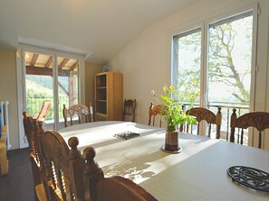 A dining area with a table, chairs, a vase with flowers, and a view through large windows. - Montserrat Figueras - 4 en-suite bedrooms - Gite 8 people (Llo)