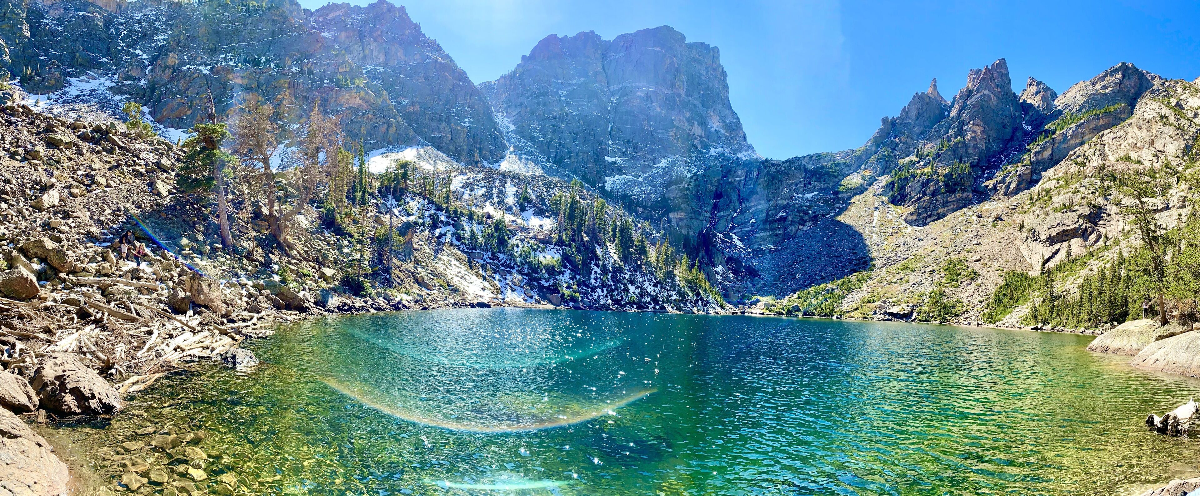 A mountainous landscape with a clear lake surrounded by rocky terrain and sparse vegetation.