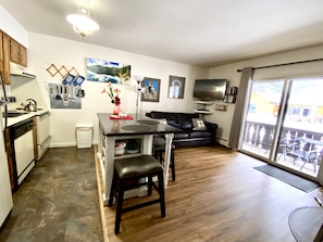 A compact living space with a kitchenette, a dining area, a sofa, and a TV.