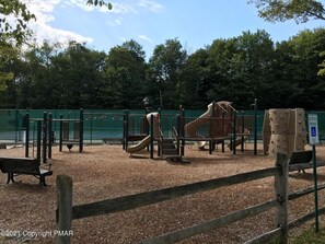 Explore the playground area with slides and climbing elements, a bench, and a designated parking area.