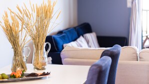 A living room with a sofa, a coffee table with a vase of wheat stalks, and a plate with fruits and nuts. - 5m walk to sandy beach, restaurants & shops! (Rethymno)