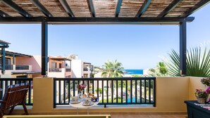 A balcony with a table set for breakfast, overlooking a pool and ocean view. - 5m walk to sandy beach, restaurants & shops! (Rethymno)