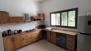 Una cocina moderna con armarios de madera, un refrigerador de acero inoxidable y un ventanal que proporciona luz natural.