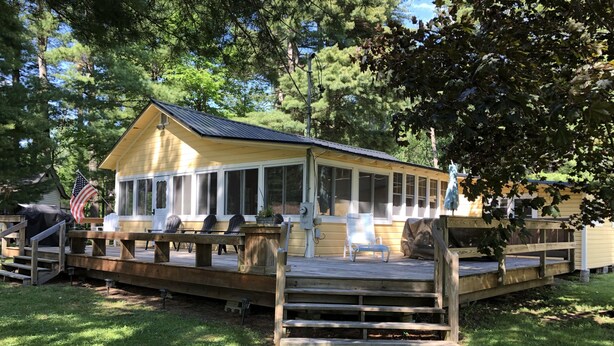 A wooden deck with a covered seating area and a flag. - Spacious Cottage with Lake Access in quiet lakeside community (Georgia)
