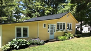 A yellow single-story house with a dark roof, white trim, and a front door. - Spacious Cottage with Lake Access in quiet lakeside community (Georgia)