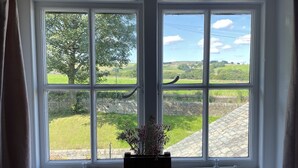 A window with a view of a stone wall and greenery. - Traditional cottage with stunning views and walks on the doorstep. (Holmbridge)