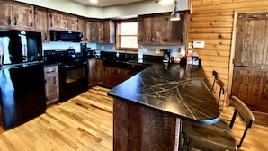 Una cocina moderna con armarios de madera, encimera negra y una isla integrada.